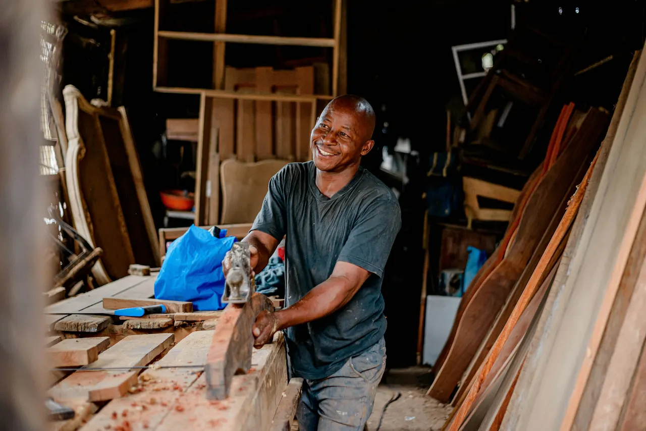 A smiling carpenter at work in his wood shop